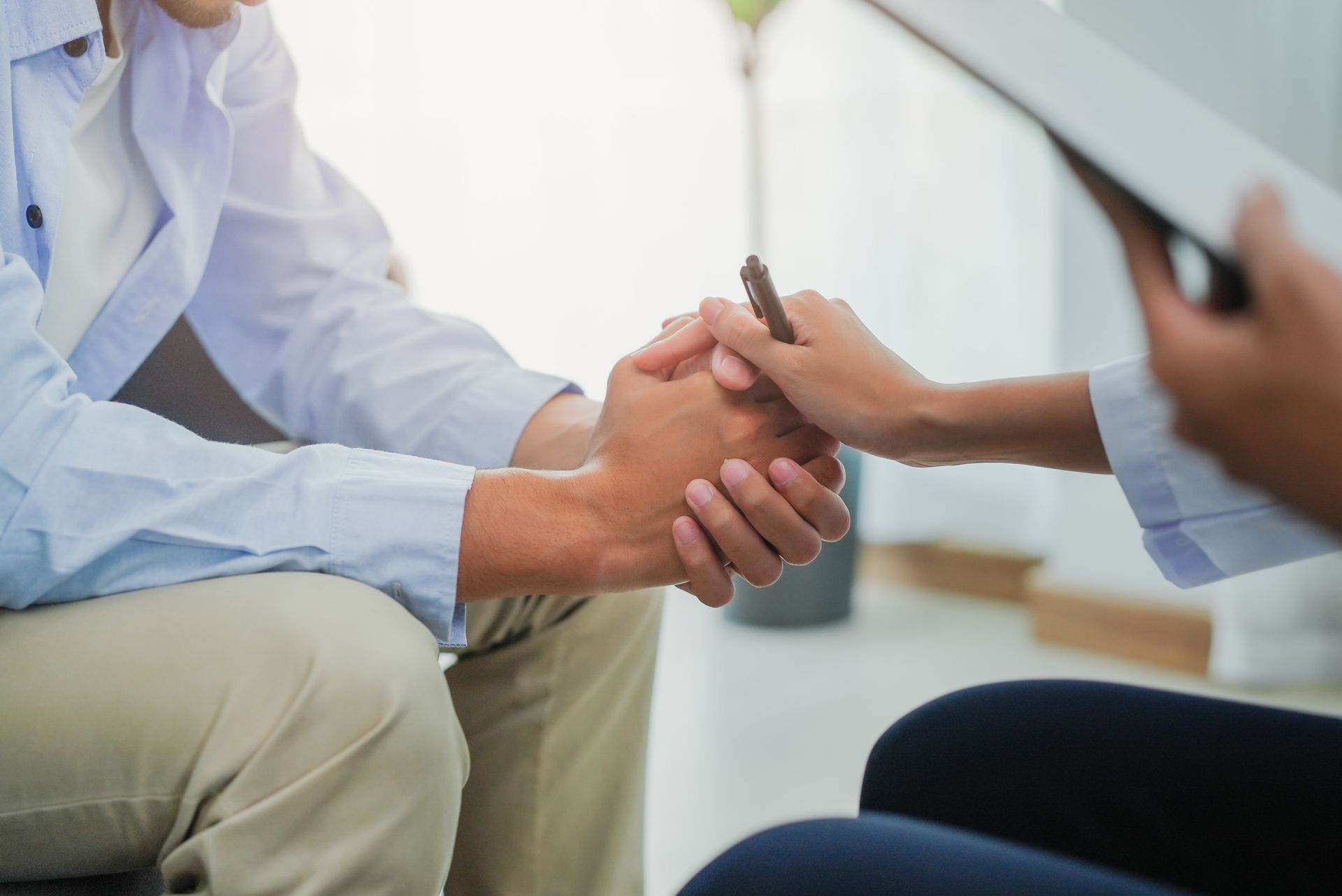 Person holding someone’s hands during a supportive counseling session.