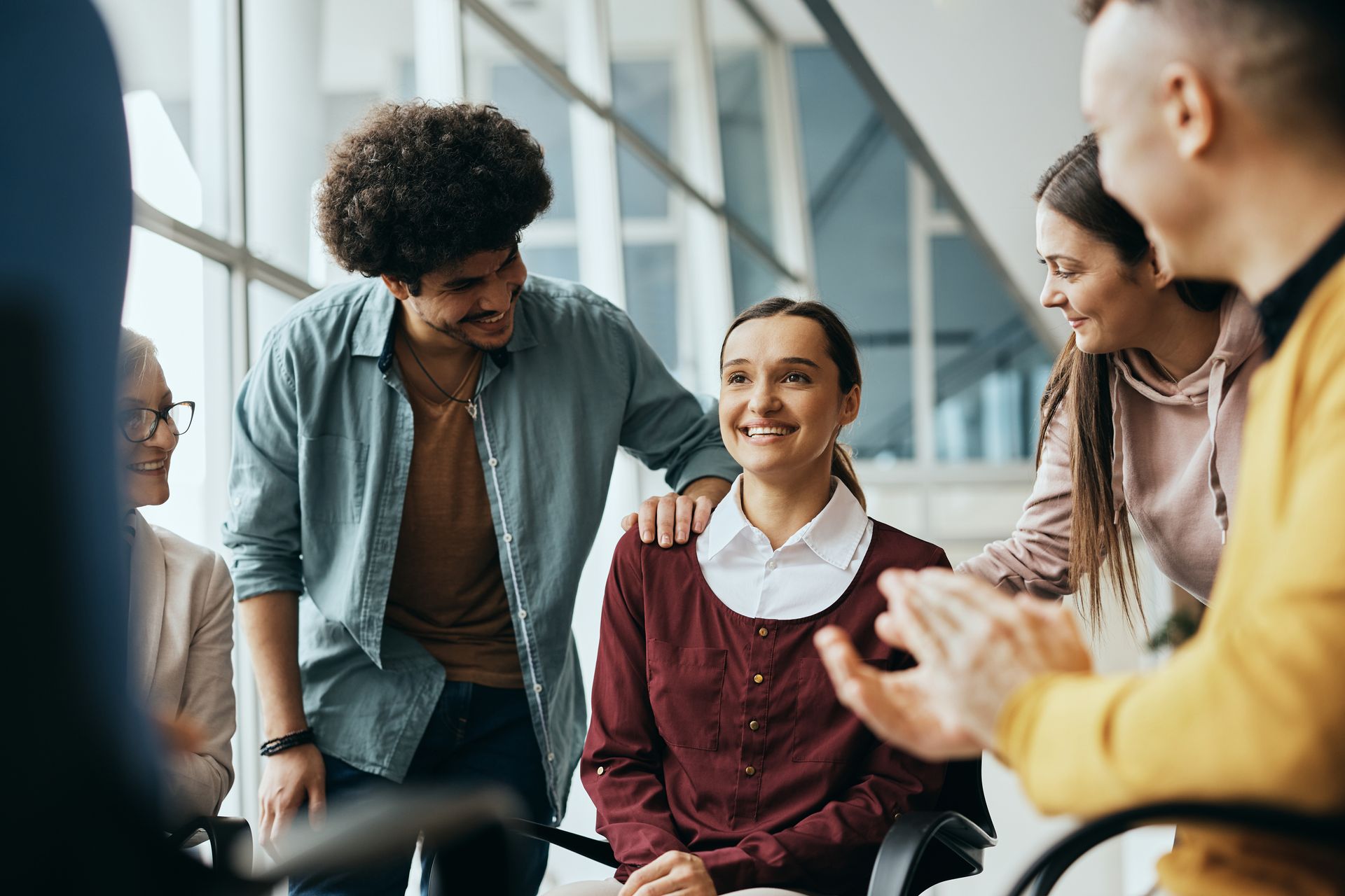 Group of people gathered around a woman, smiling and celebrating.