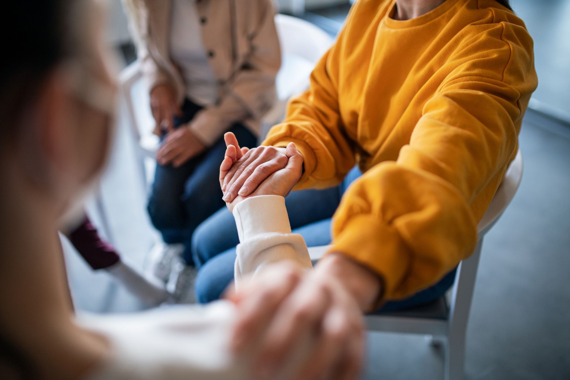 A group of people are sitting in chairs holding hands.