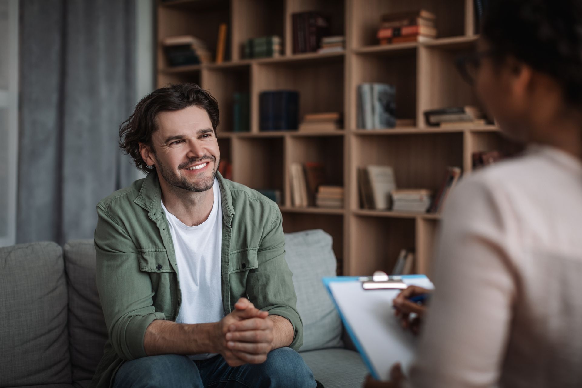 A psychologist consults a smiling guy in a modern clinic, showcasing adult mental health services.