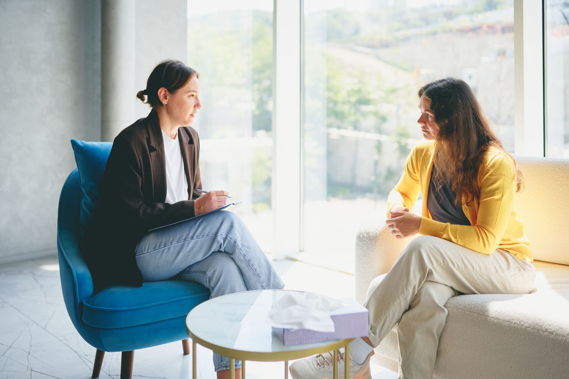 A female counselor speaks to her patient as they sit in front of each other, inside a room. A female counselor speaks to her patient as they sit in front of each other, inside a room.