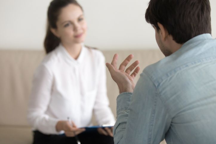Female psychologist consulting male patient, showcasing psychiatric services in a meeting.
