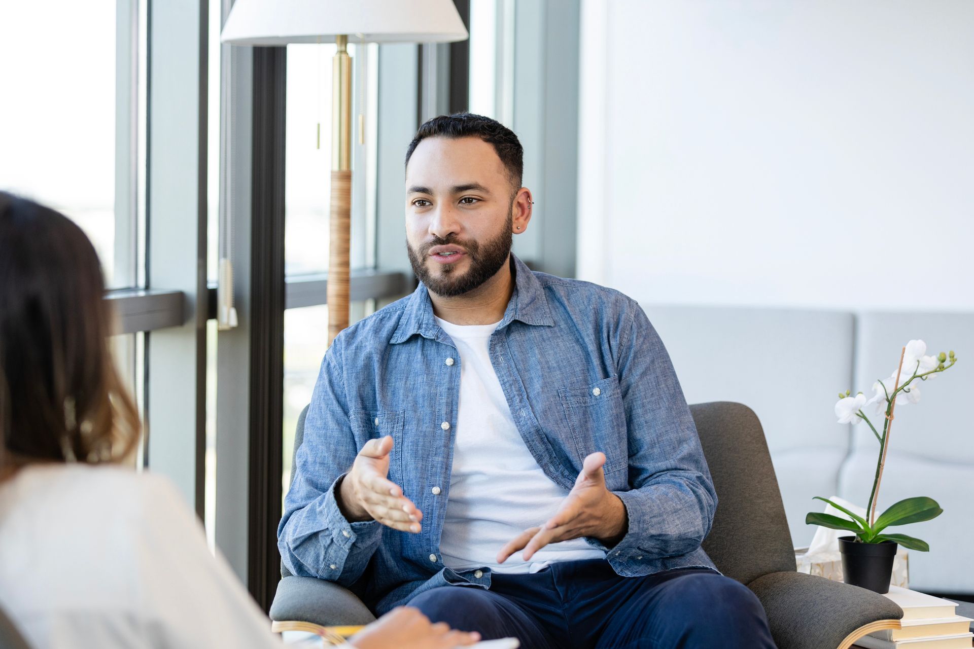 A young man gestures as he shares something during a therapy session.   