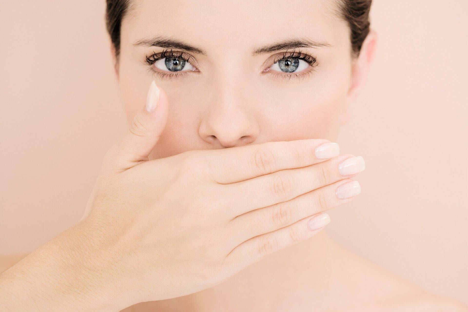 A woman is covering her mouth with her hand.