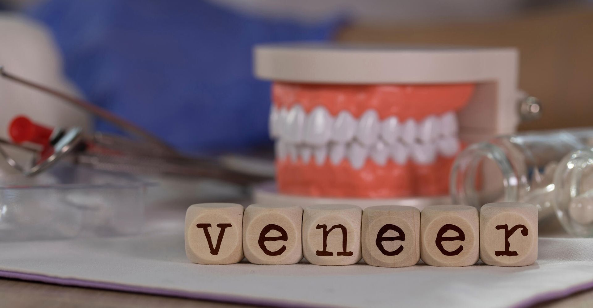 The word veneer is written on wooden blocks next to a model of teeth.