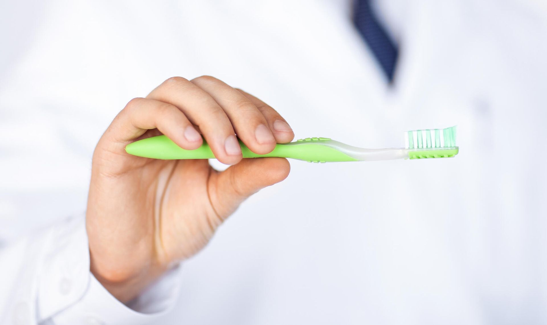 A person is holding a green toothbrush in their hand.