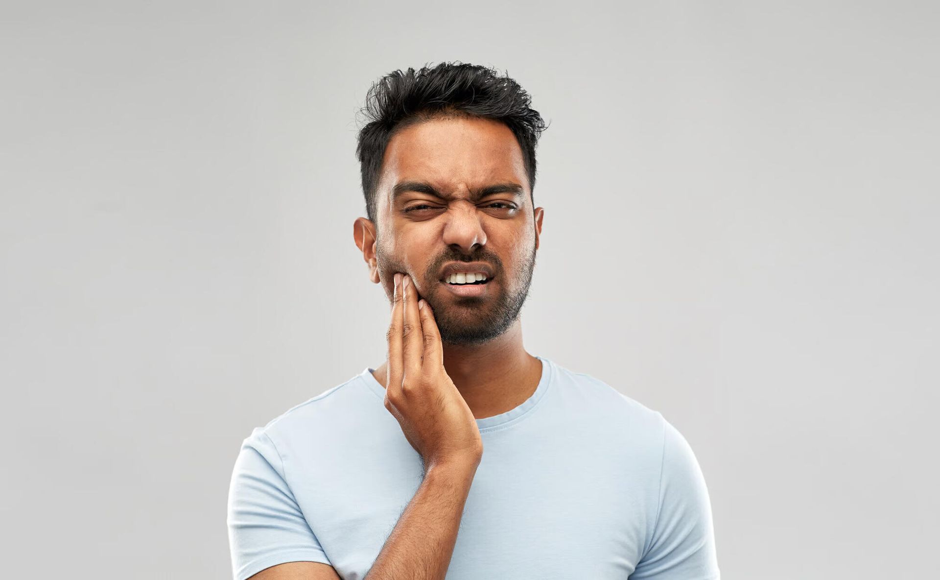 A man is holding his face in pain because of a toothache.