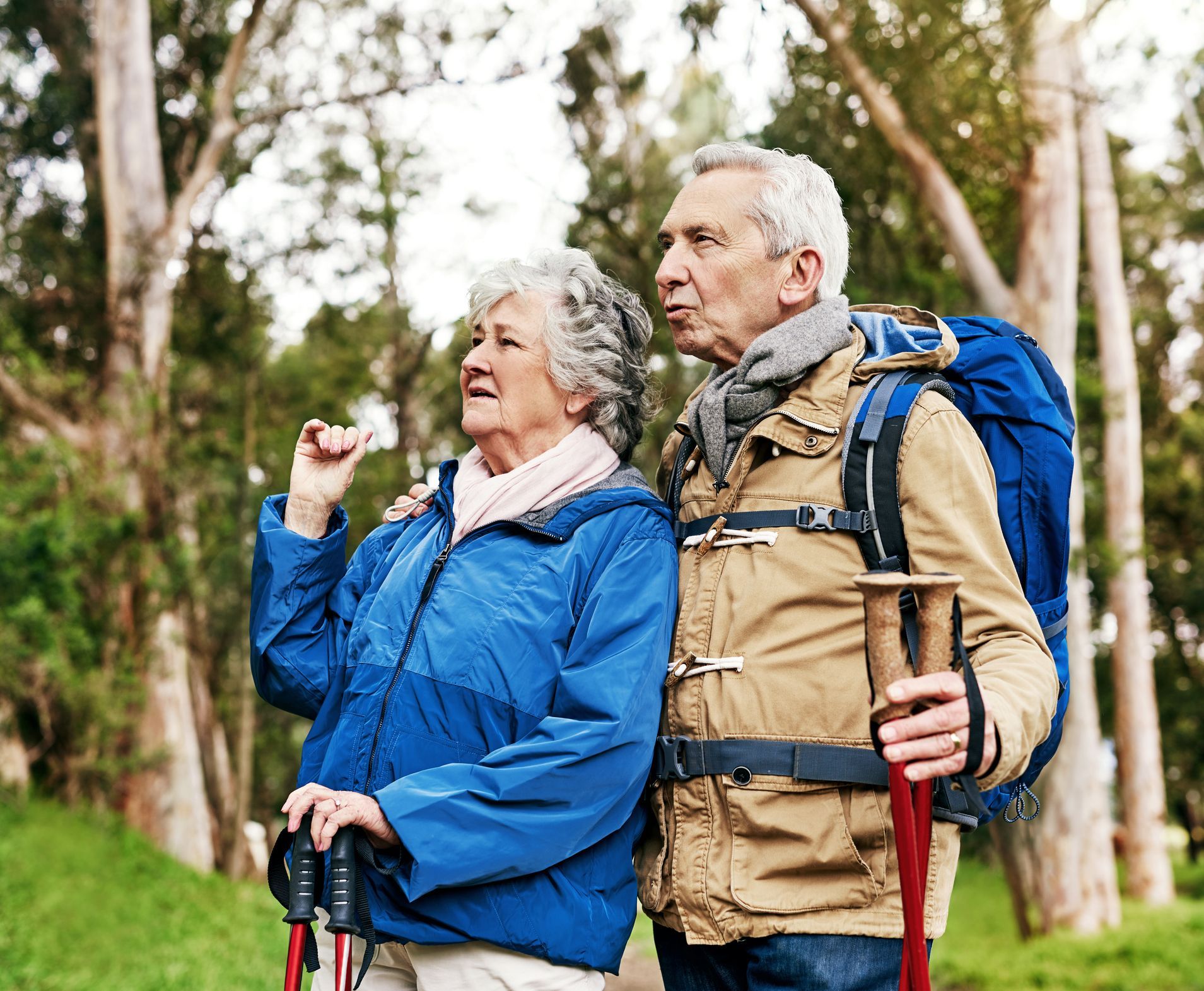 A man and a woman are hiking in the woods.