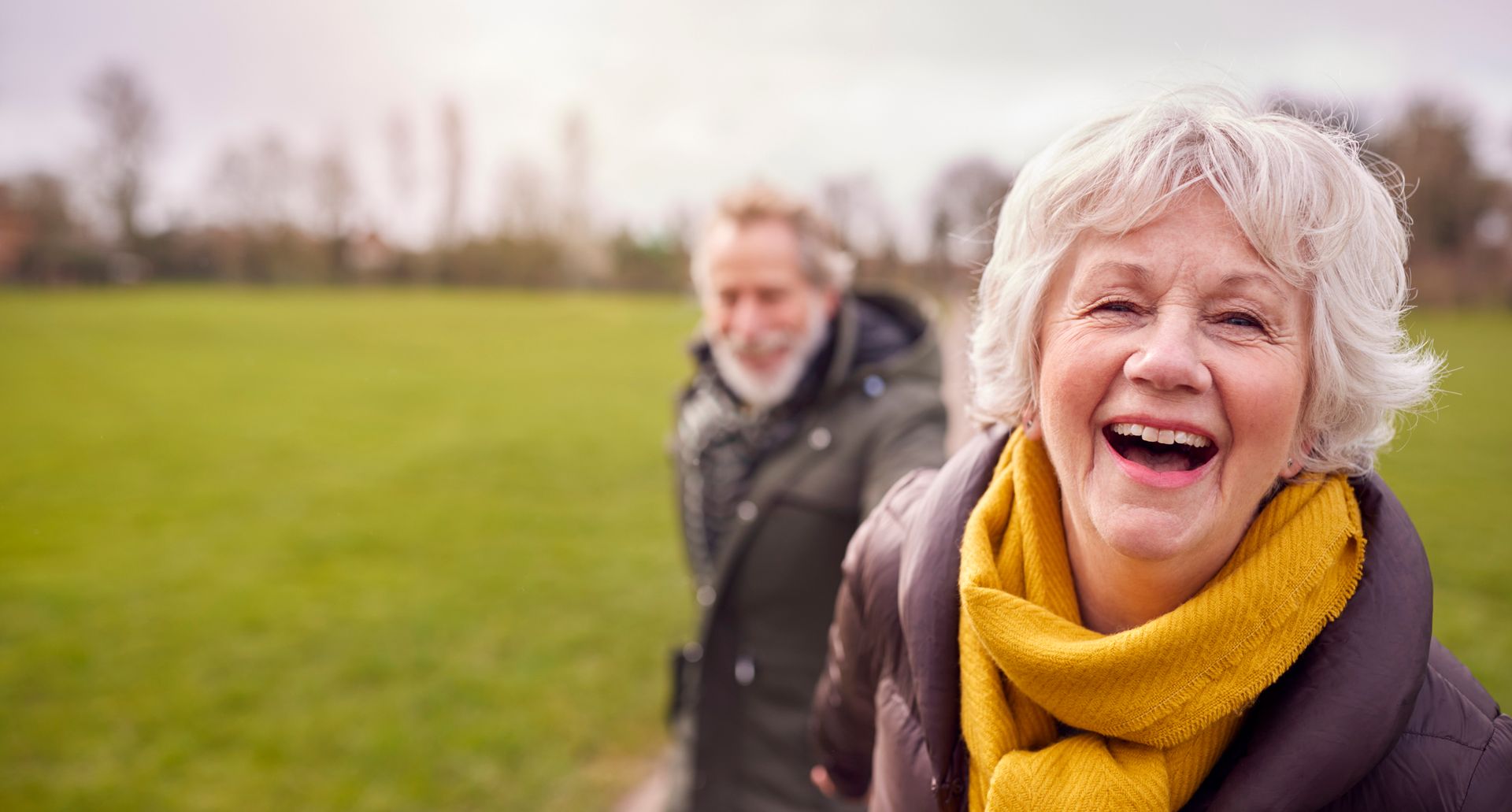 A woman is laughing while walking with a man in a field