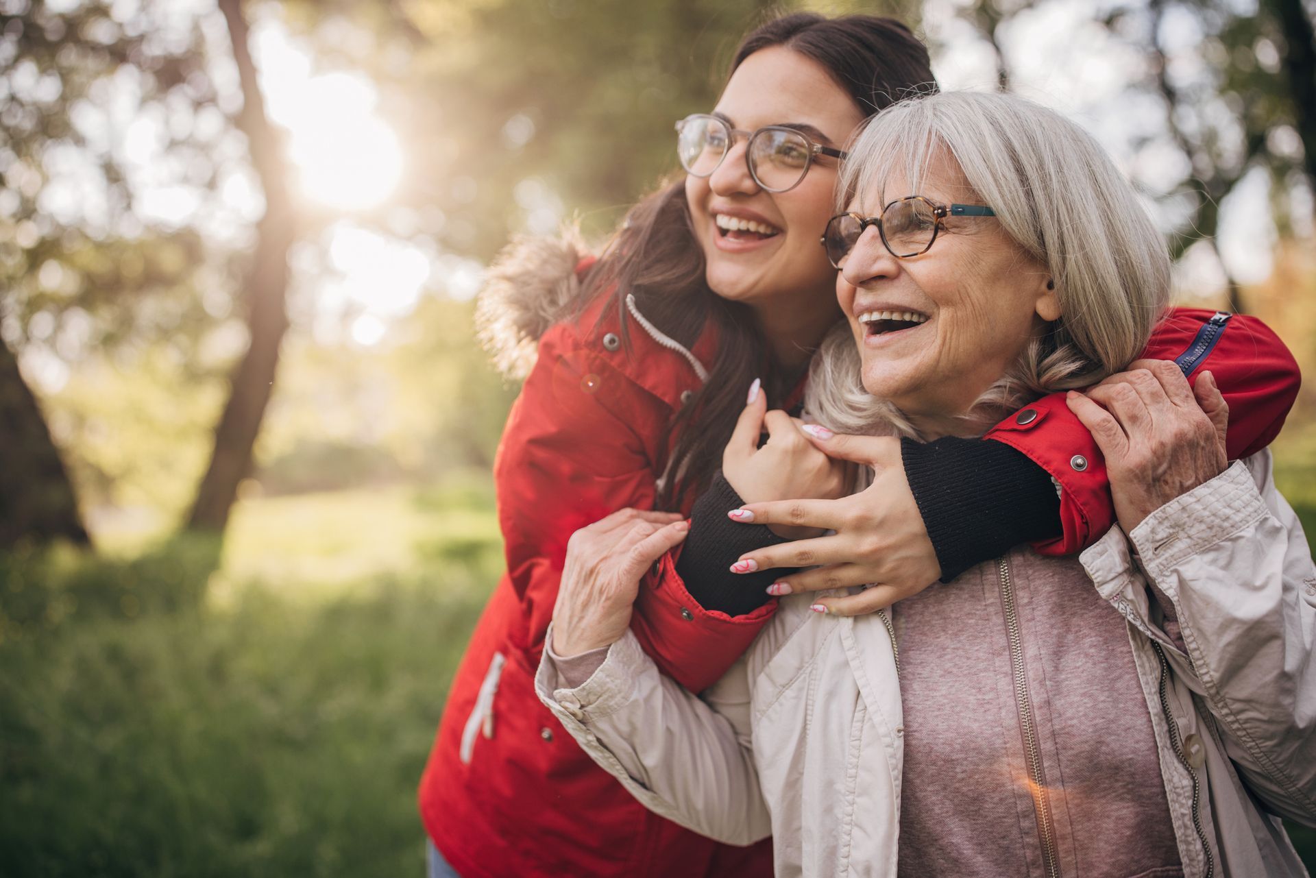 A young woman is hugging an older woman in a park
