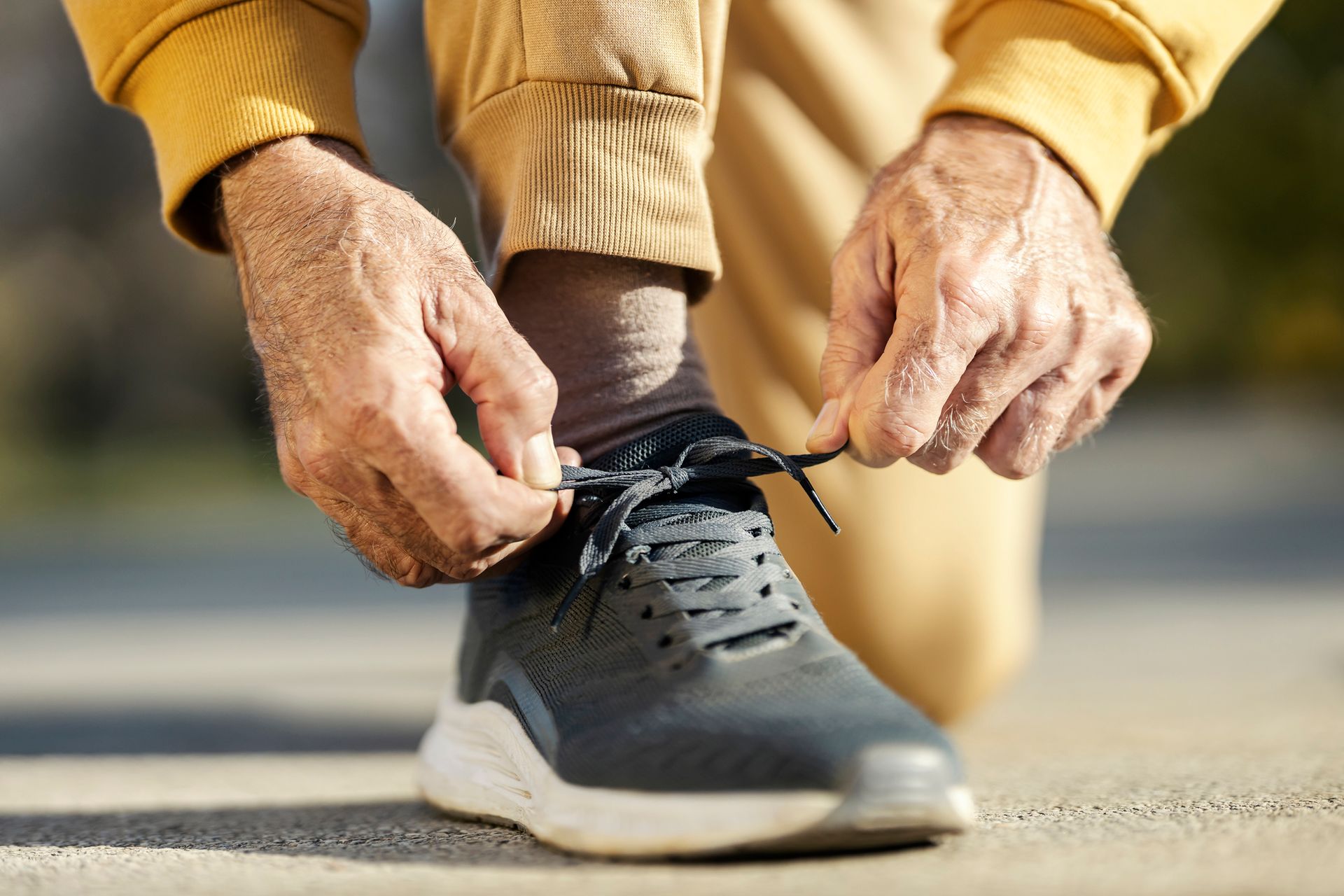 A man is tying his shoes on a sidewalk