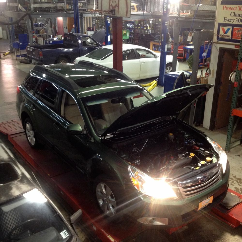 A car with the hood open is in a garage