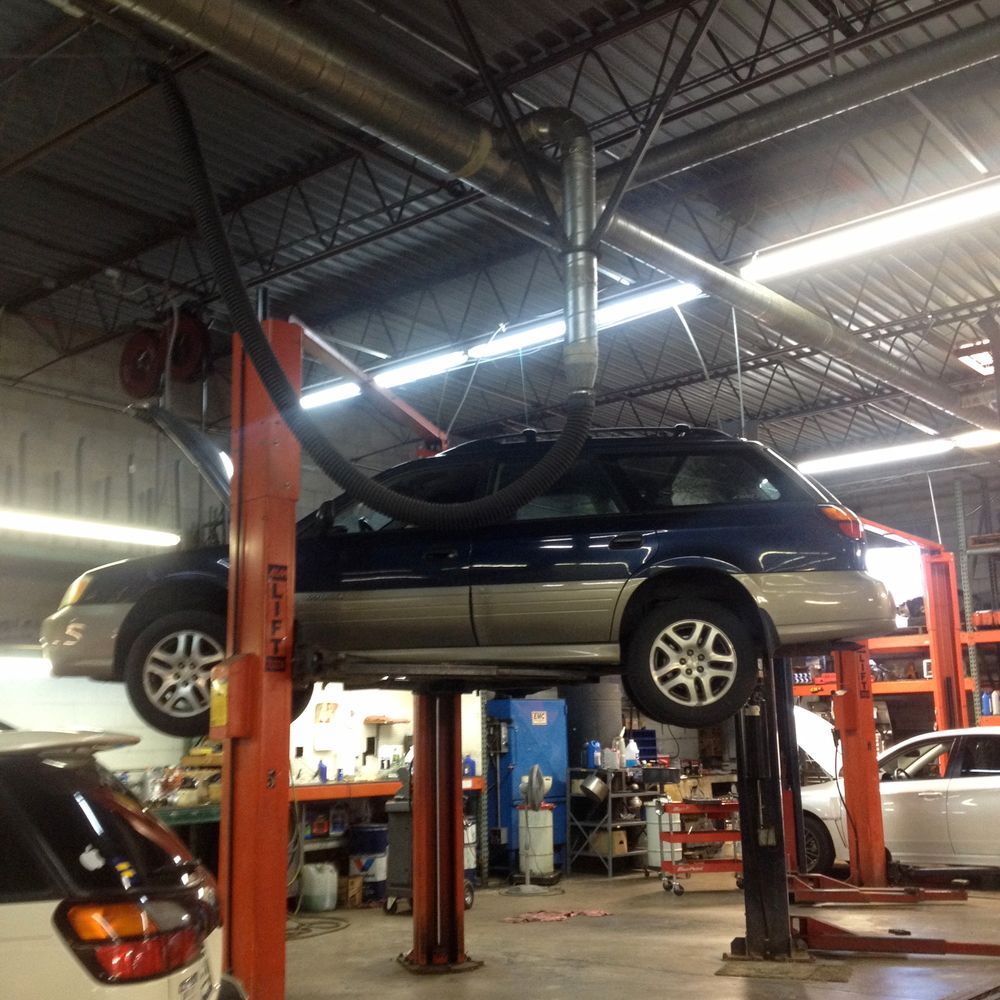 A blue suv is on a lift in a garage