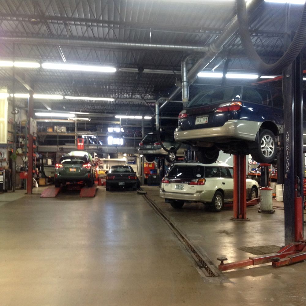 A row of cars are being worked on in a garage