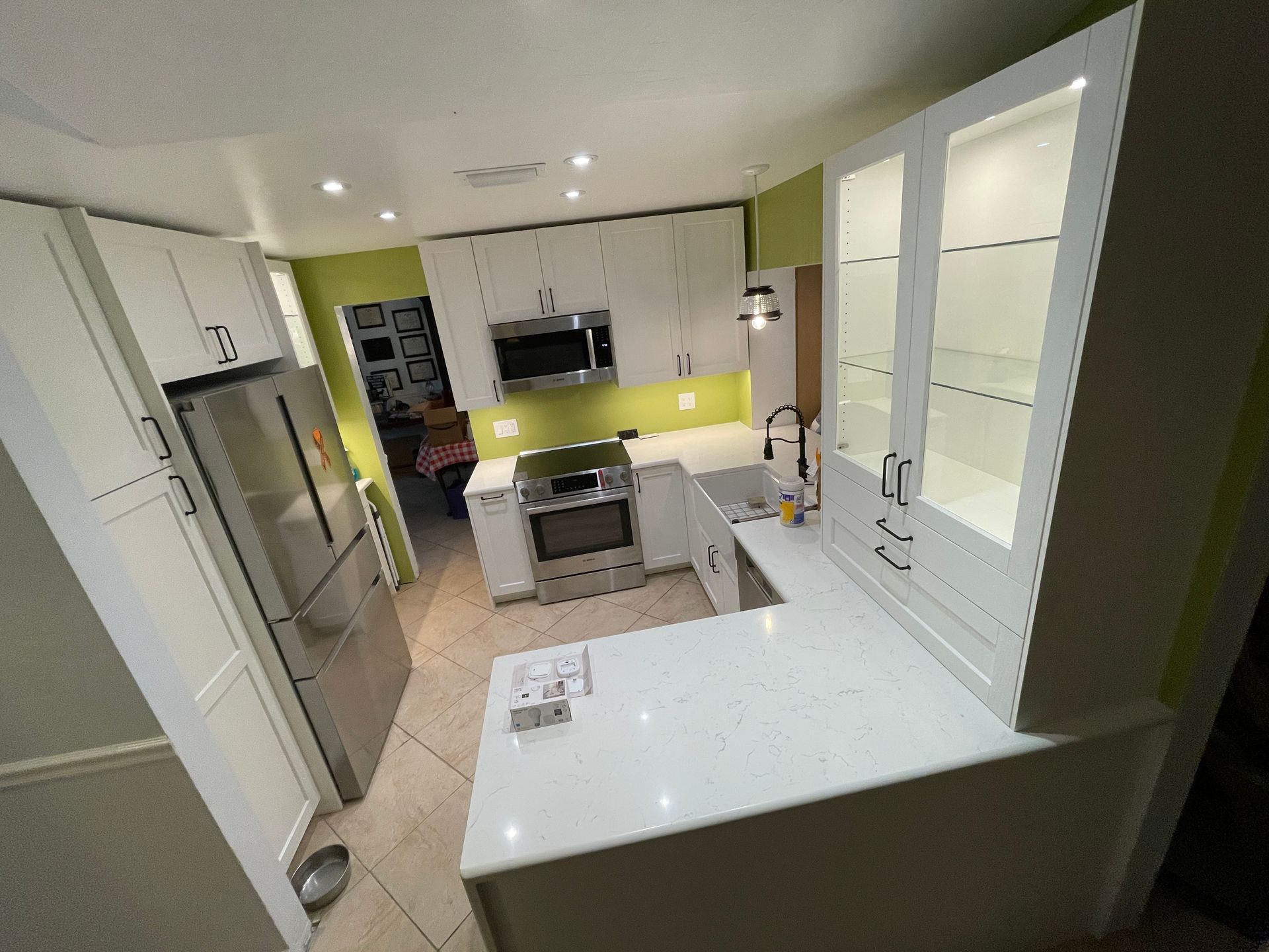 Modern white kitchen with stainless steel appliances, white countertops, and white cabinets.
