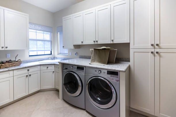 Laundry room with white cabinets, granite countertop, front-load washer/dryer, and a window.