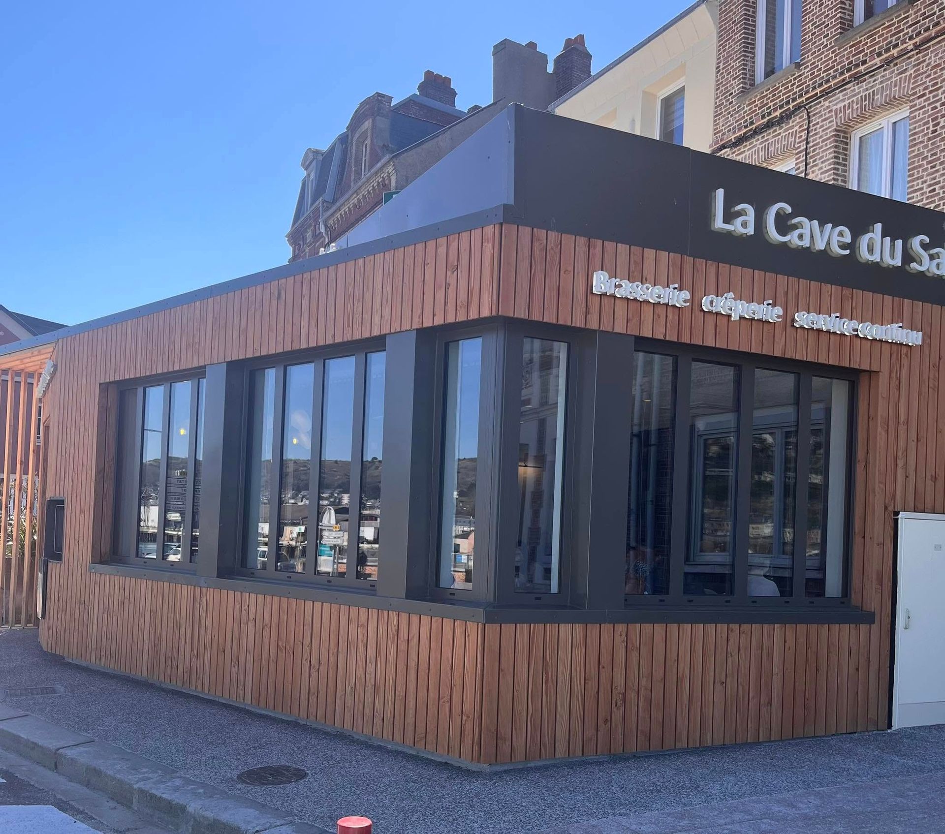 Un restaurant moderne appelé « La Cave du Saumon », avec un revêtement en bois brun et de grandes fenêtres.