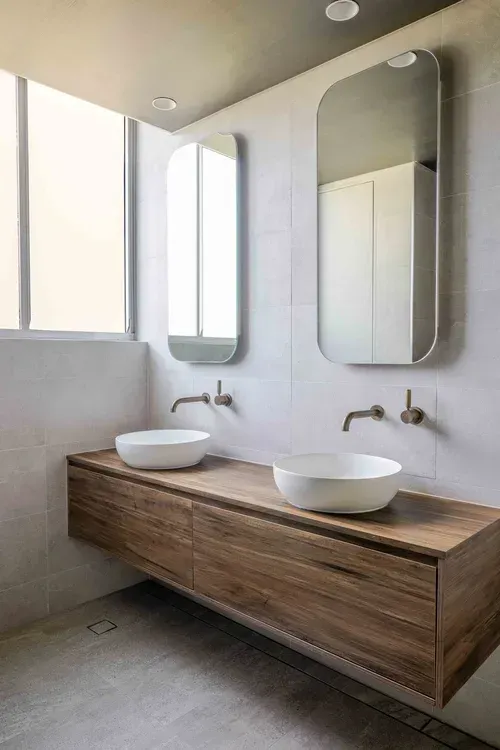 Modern bathroom vanity with two vessel sinks, wall faucets, and vertical mirrors