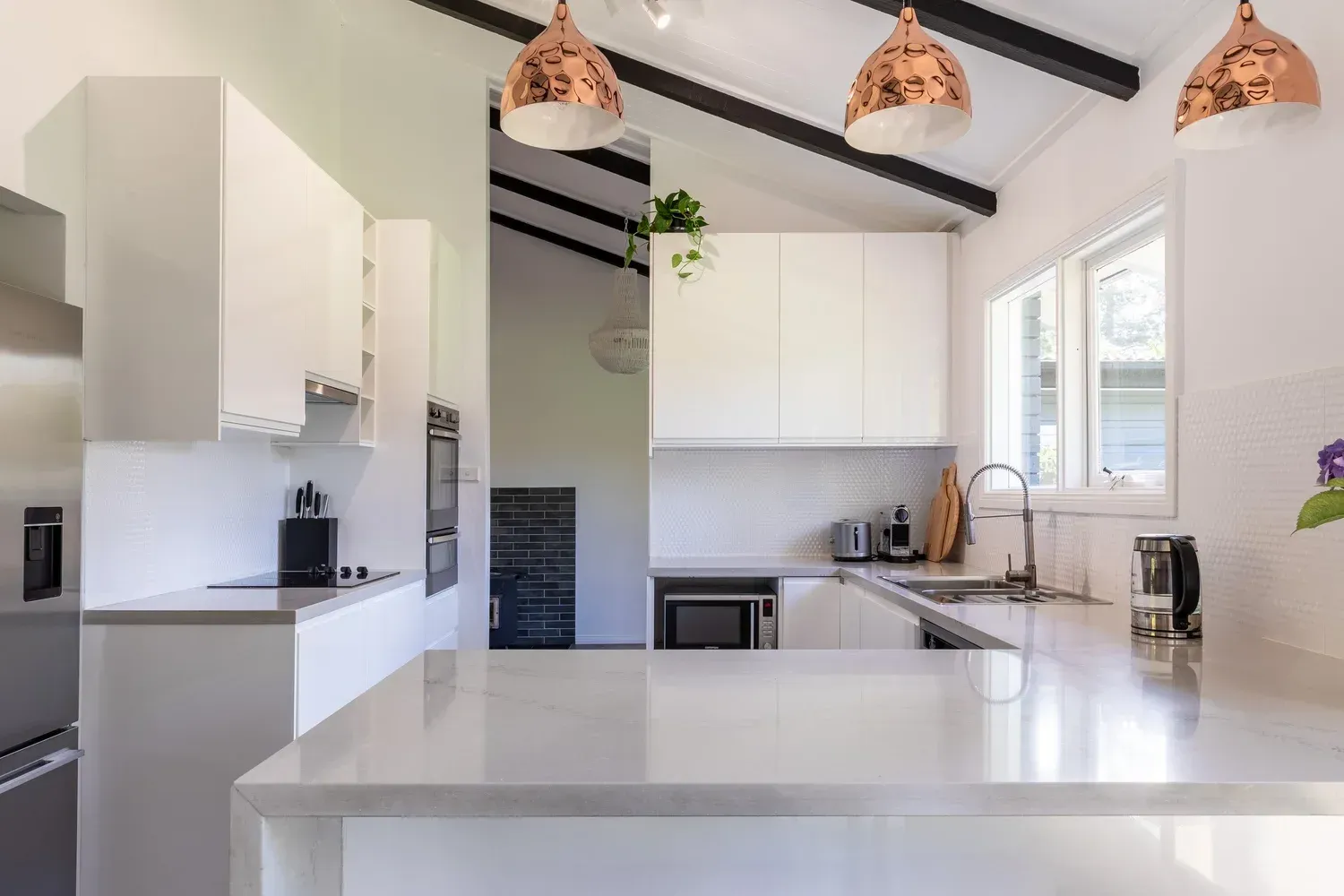 Bright modern white kitchen with island, pendant lights, and vaulted ceiling