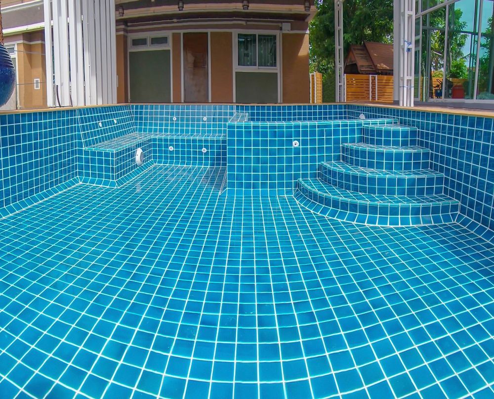 An Empty Swimming Pool Lined With Blue Square Tiles — Hobart Tiling Solutions In Clarendon Vale, TAS