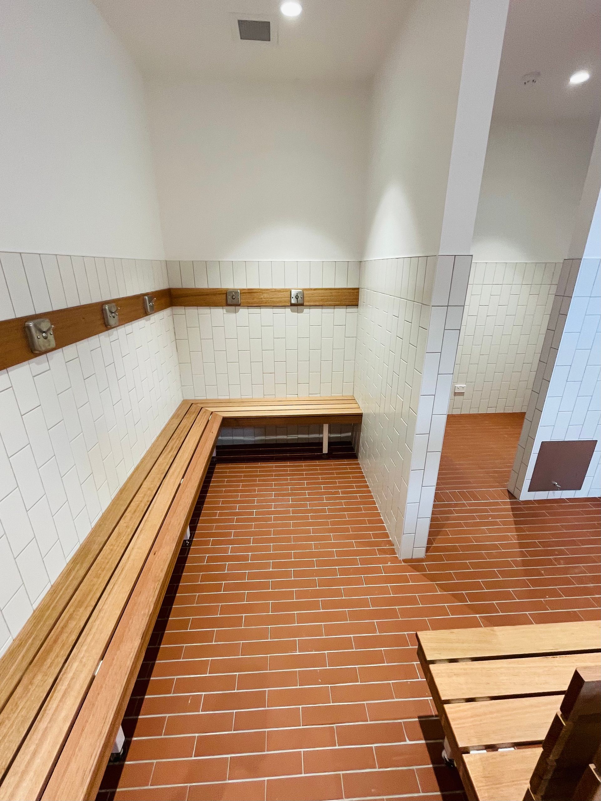 A Locker Room Featuring a Long Wooden Bench — Hobart Tiling Solutions In Clarendon Vale, TAS