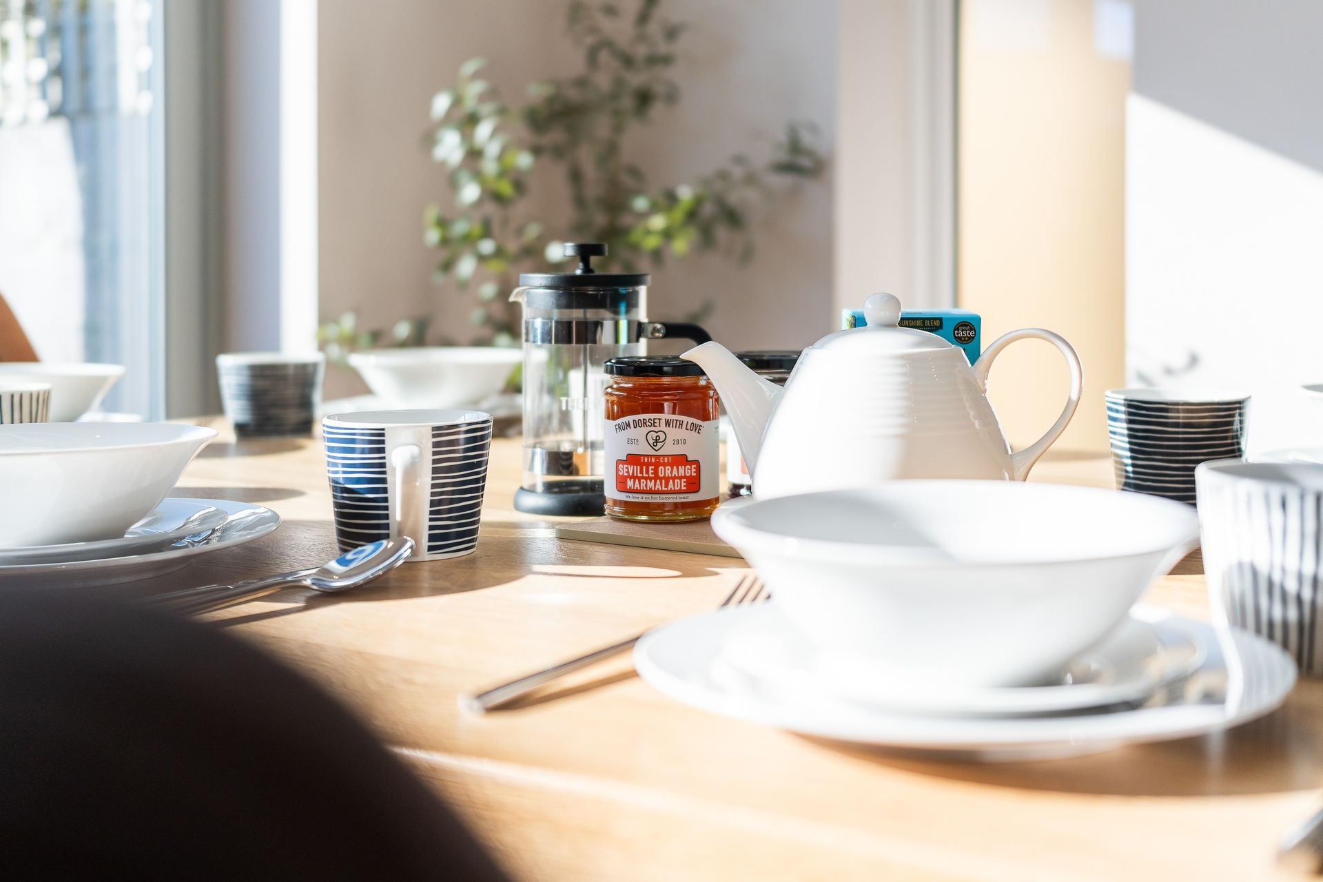 A table with plates , bowls , and a jar of jam on it.
