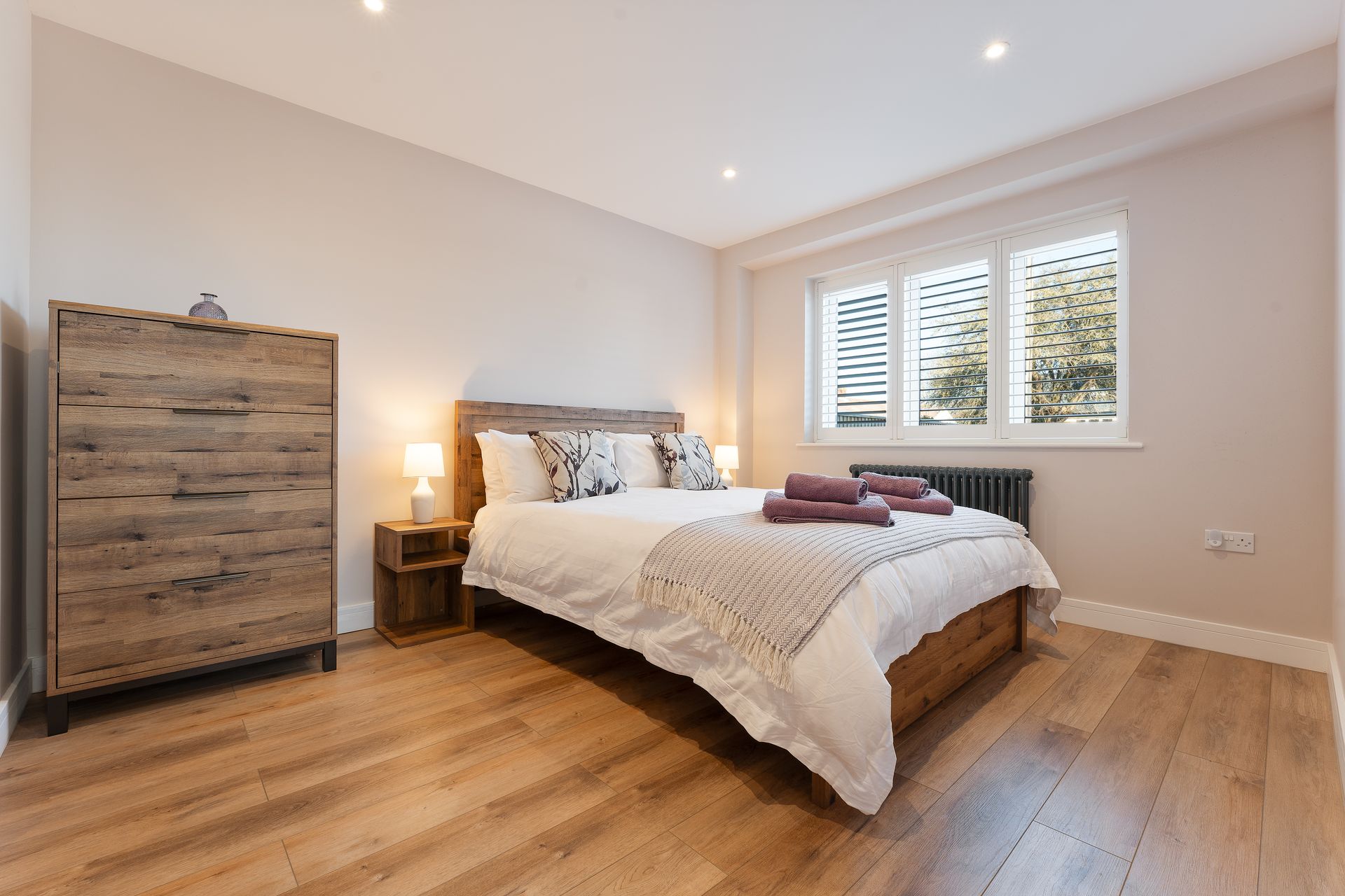 A bedroom with a bed , dresser , and window.