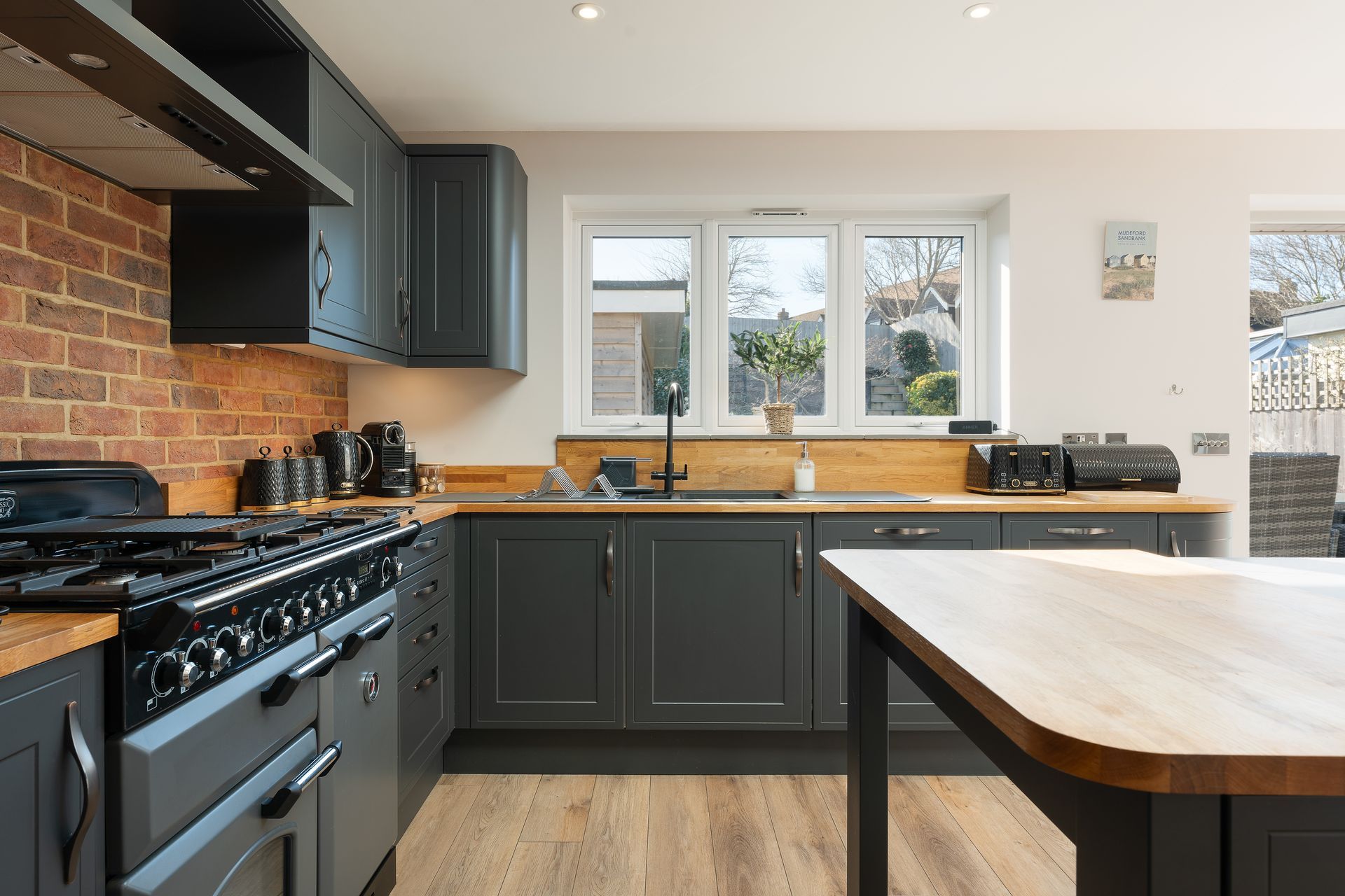 A kitchen with a stove , sink , cabinets and a table.