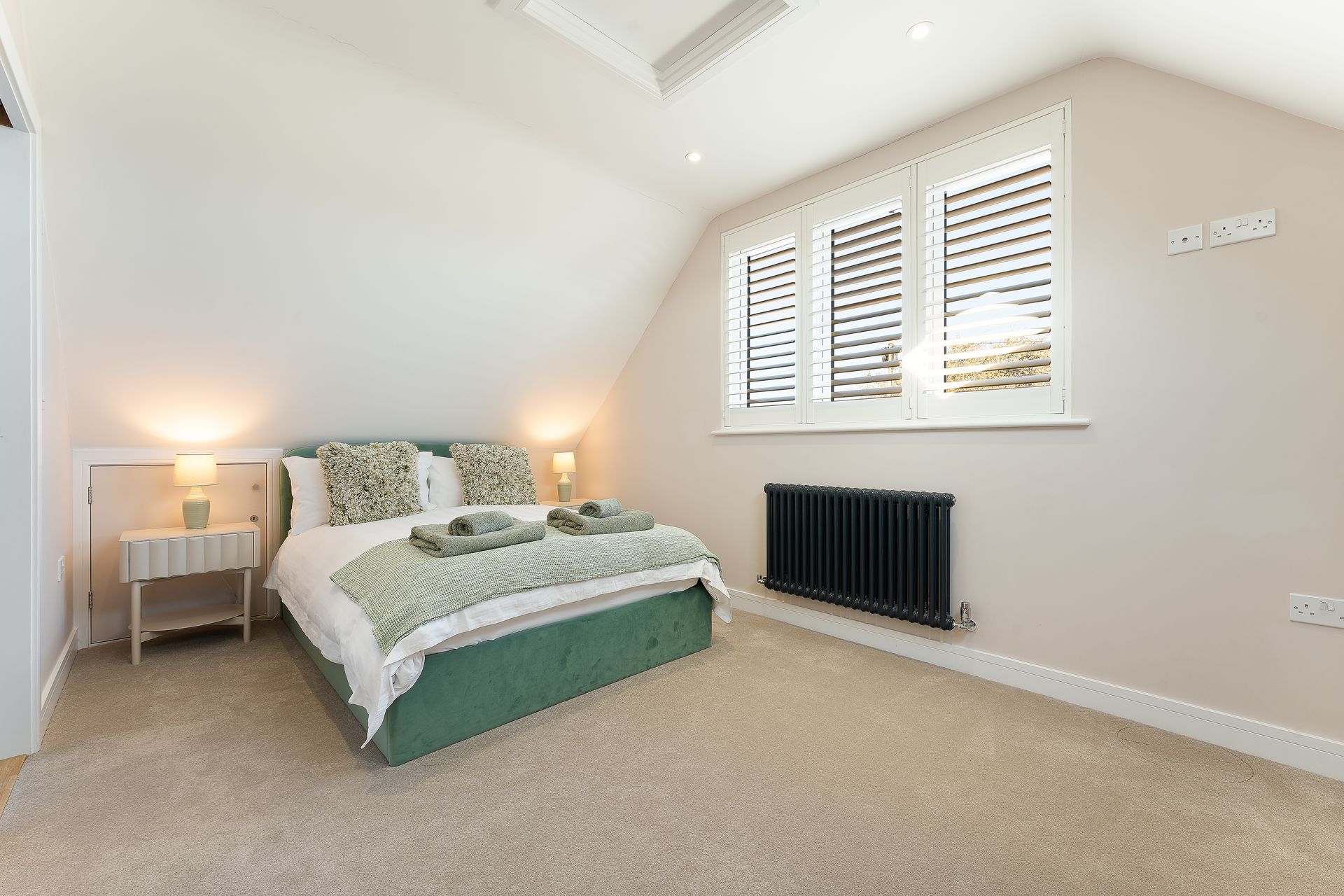 A bedroom with a bed , nightstand , and radiator.