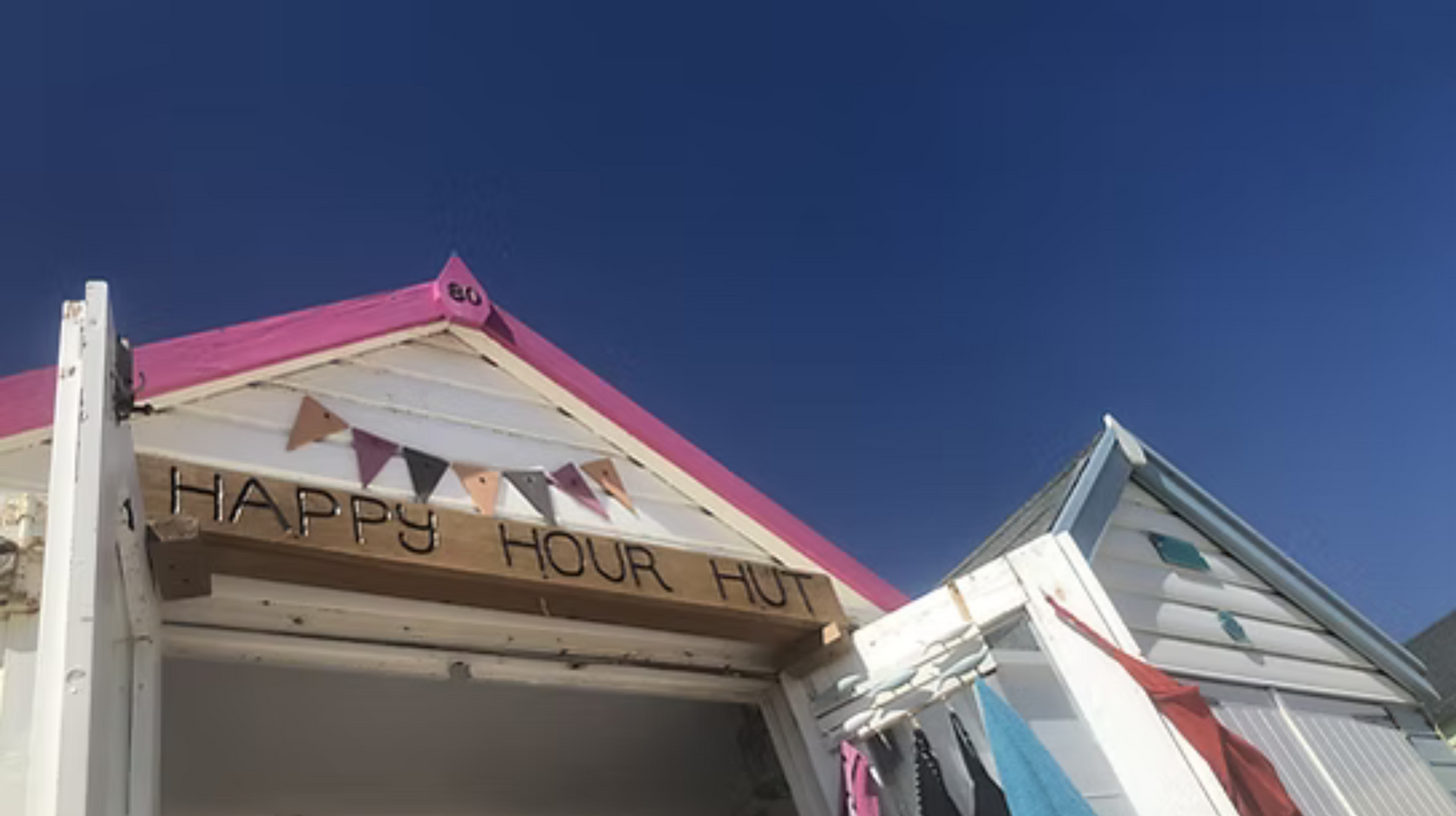 A beach hut with a sign that says `` happy hour hut ''.
