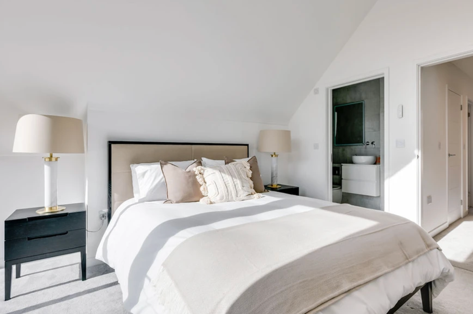 A bedroom with a bed , nightstand , lamps and a bathroom.