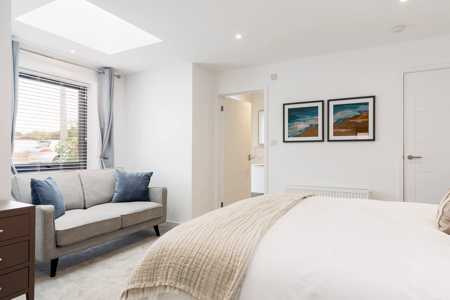 A bedroom with a bed , couch , and two pictures on the wall.