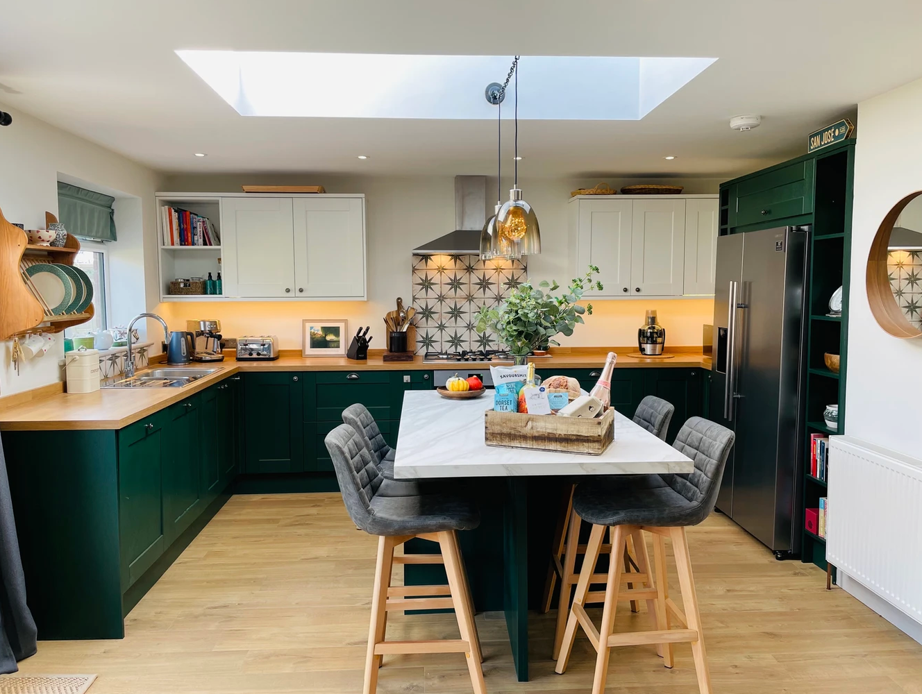 A kitchen with green cabinets and a large island in the middle.