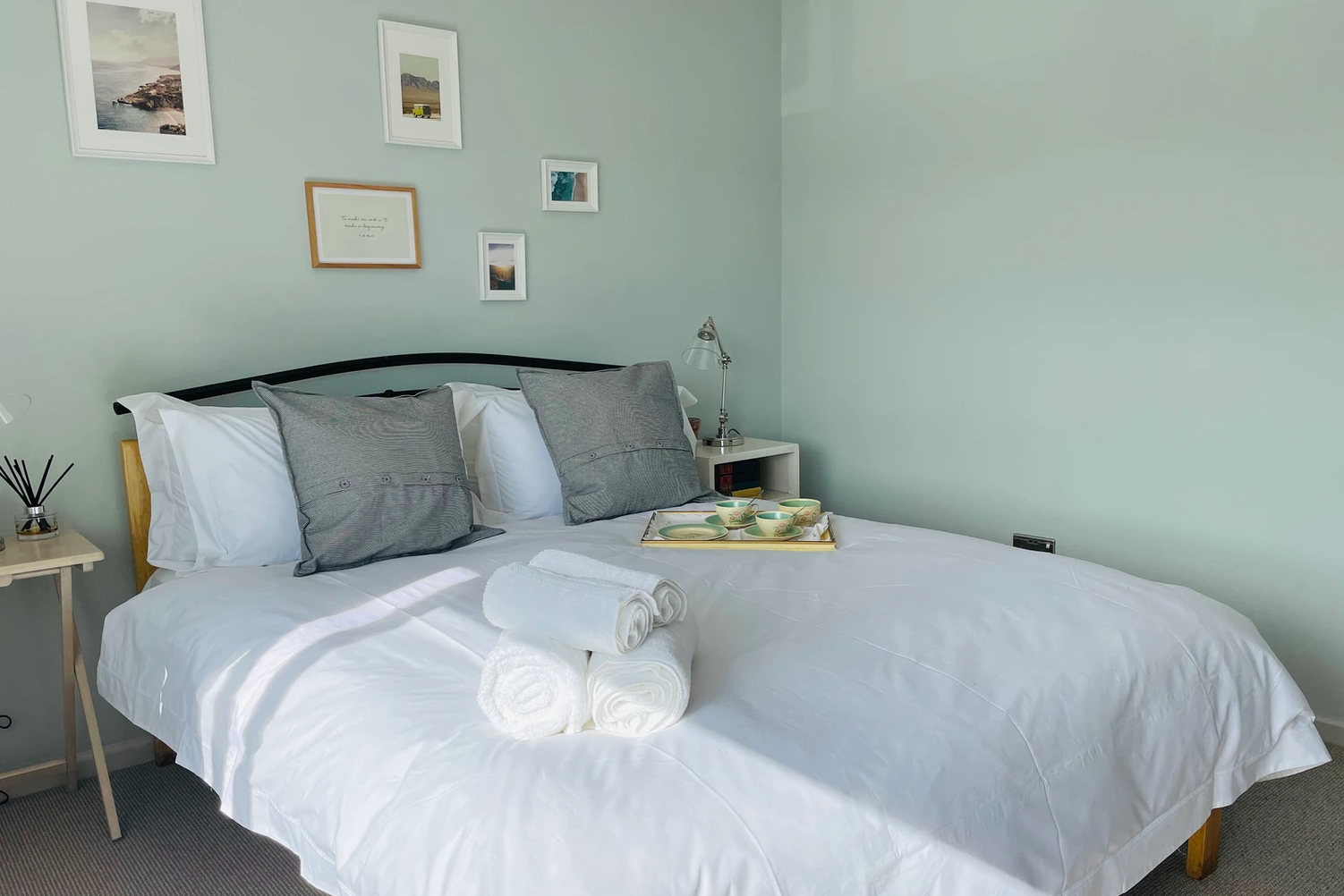 A bed with white sheets and pillows in a bedroom with a tray on it.