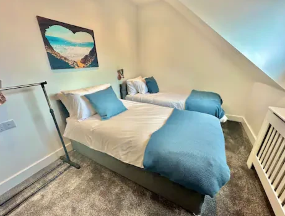 A bedroom with two beds and a painting on the wall.