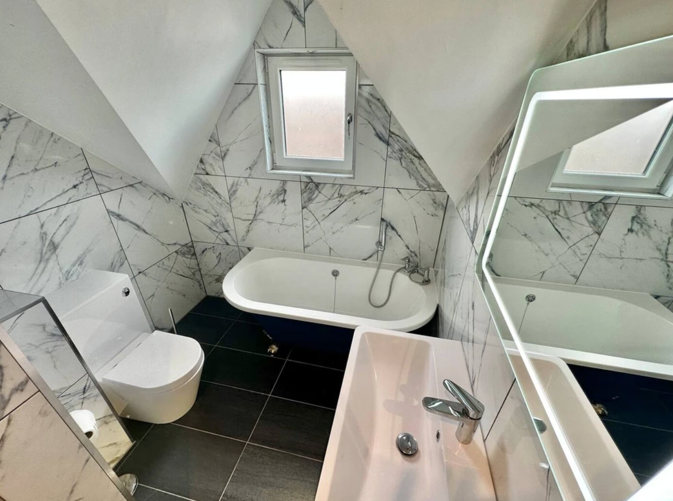 A bathroom with a tub , sink , toilet and mirror.