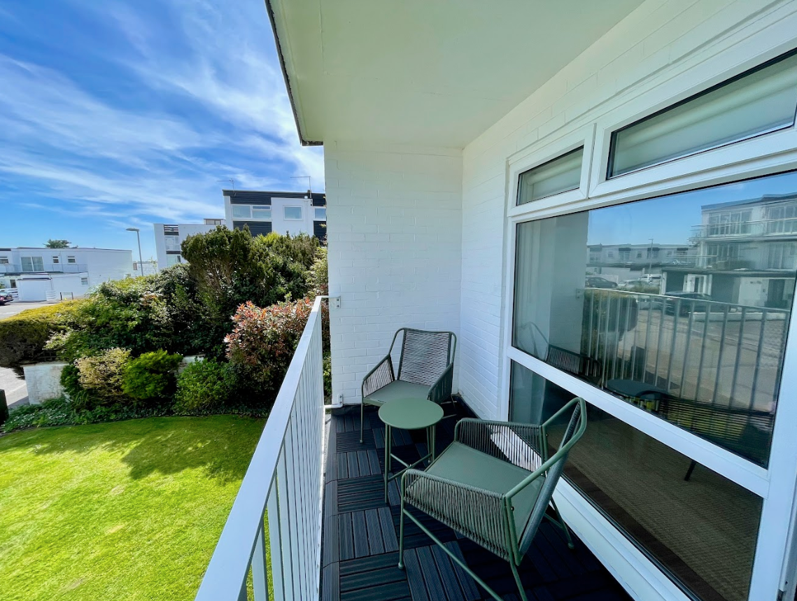 There is a balcony with chairs and a table on it.
