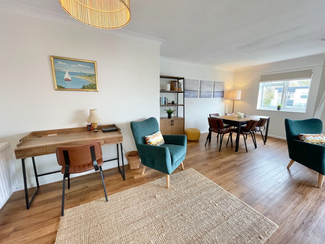 A living room with a desk , chairs , and a dining table.