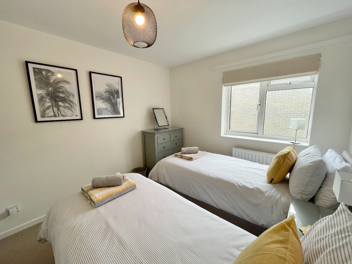 A bedroom with two twin beds and a window.
