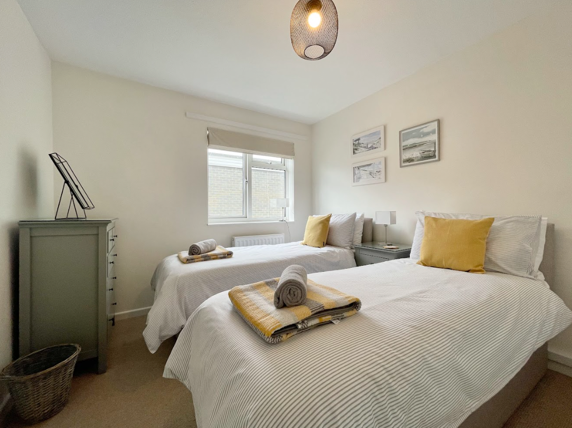 A bedroom with two twin beds and a dresser.