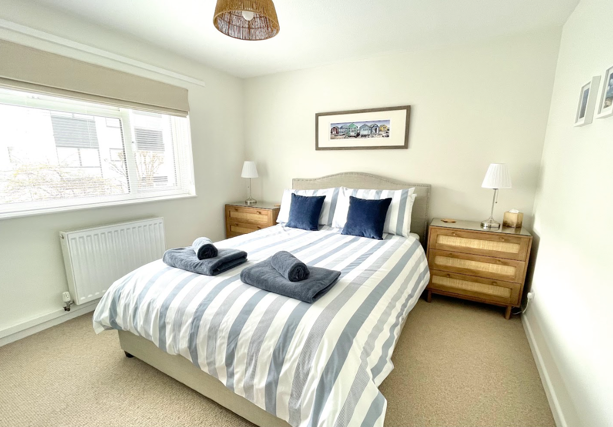 A bedroom with a bed , dresser , nightstand and window.