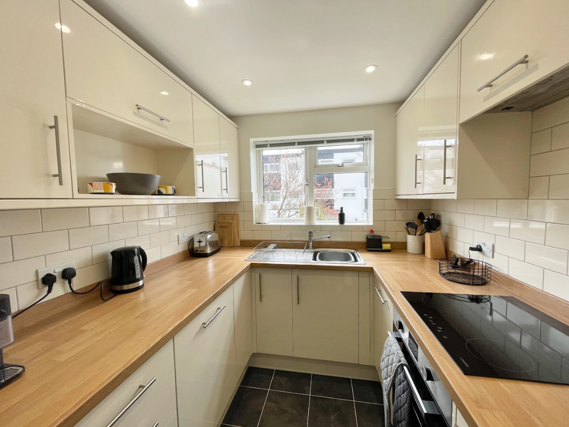 A kitchen with white cabinets and wooden counter tops