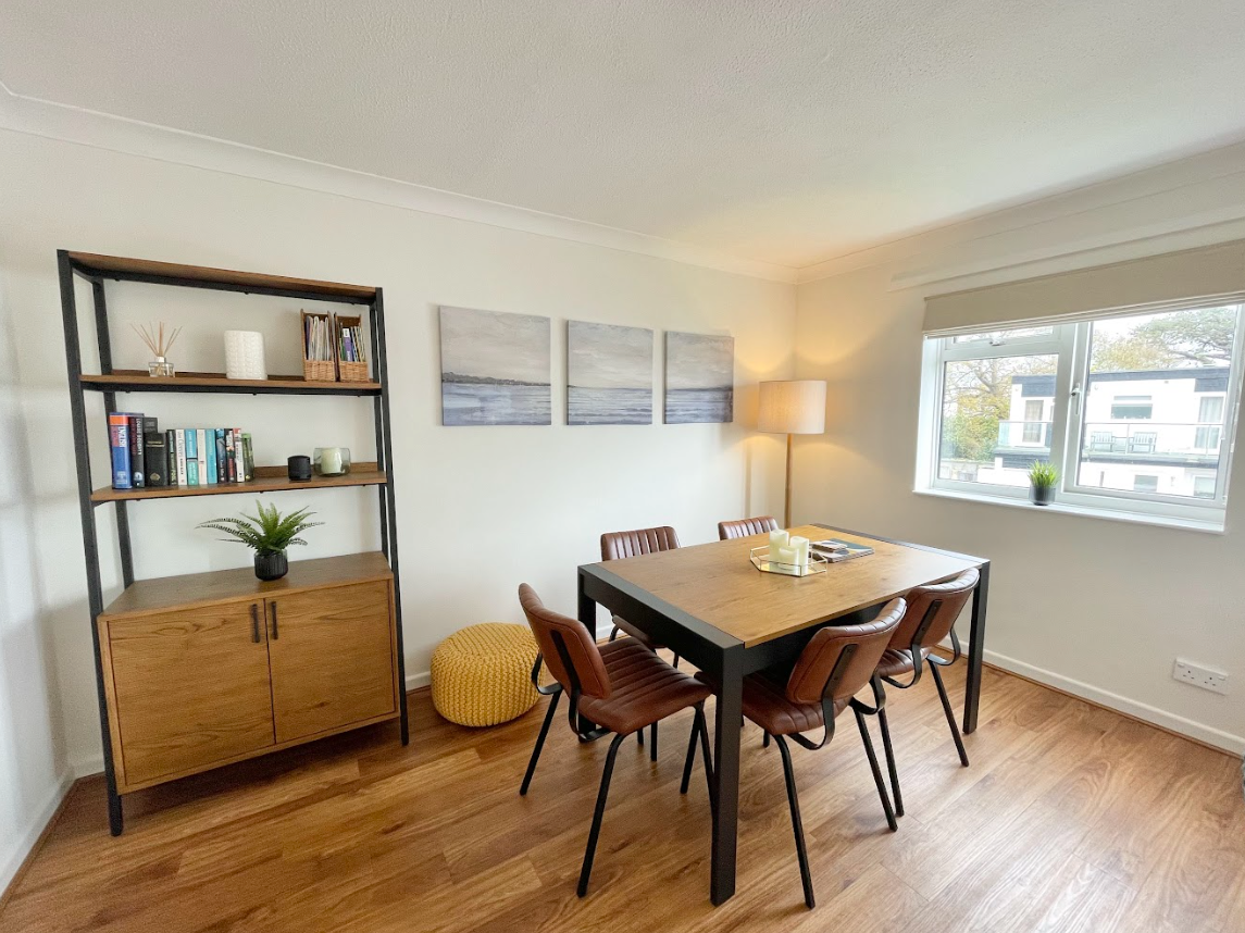 A dining room with a table and chairs and a bookshelf.