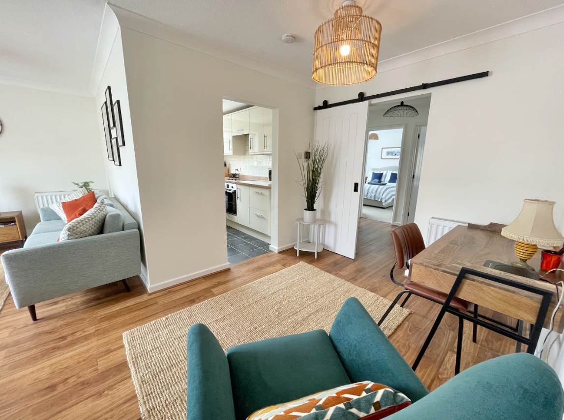 A living room with a couch , chair , desk and sliding barn door.