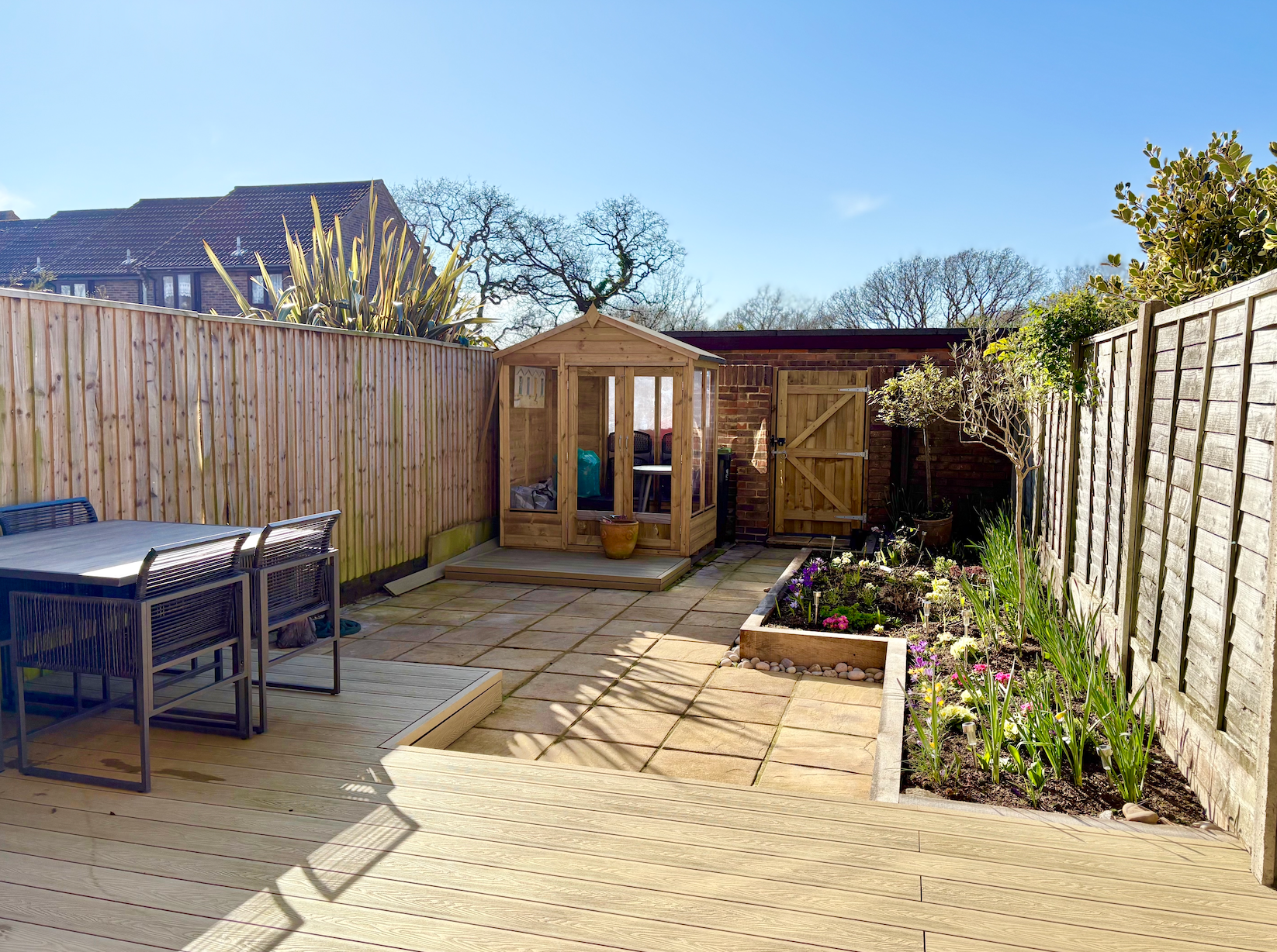 There is a wooden shed in the backyard with a table and chairs.