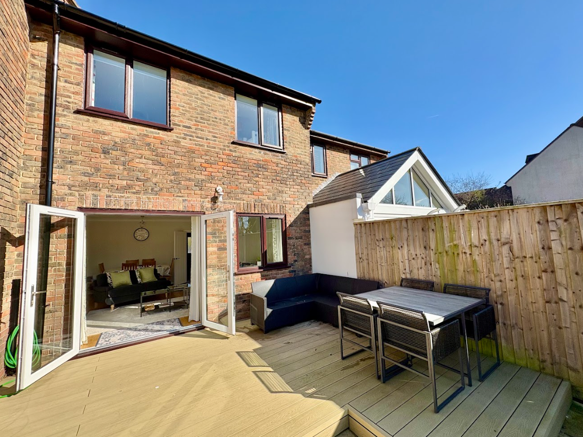 A patio with a table and chairs in front of a brick house.