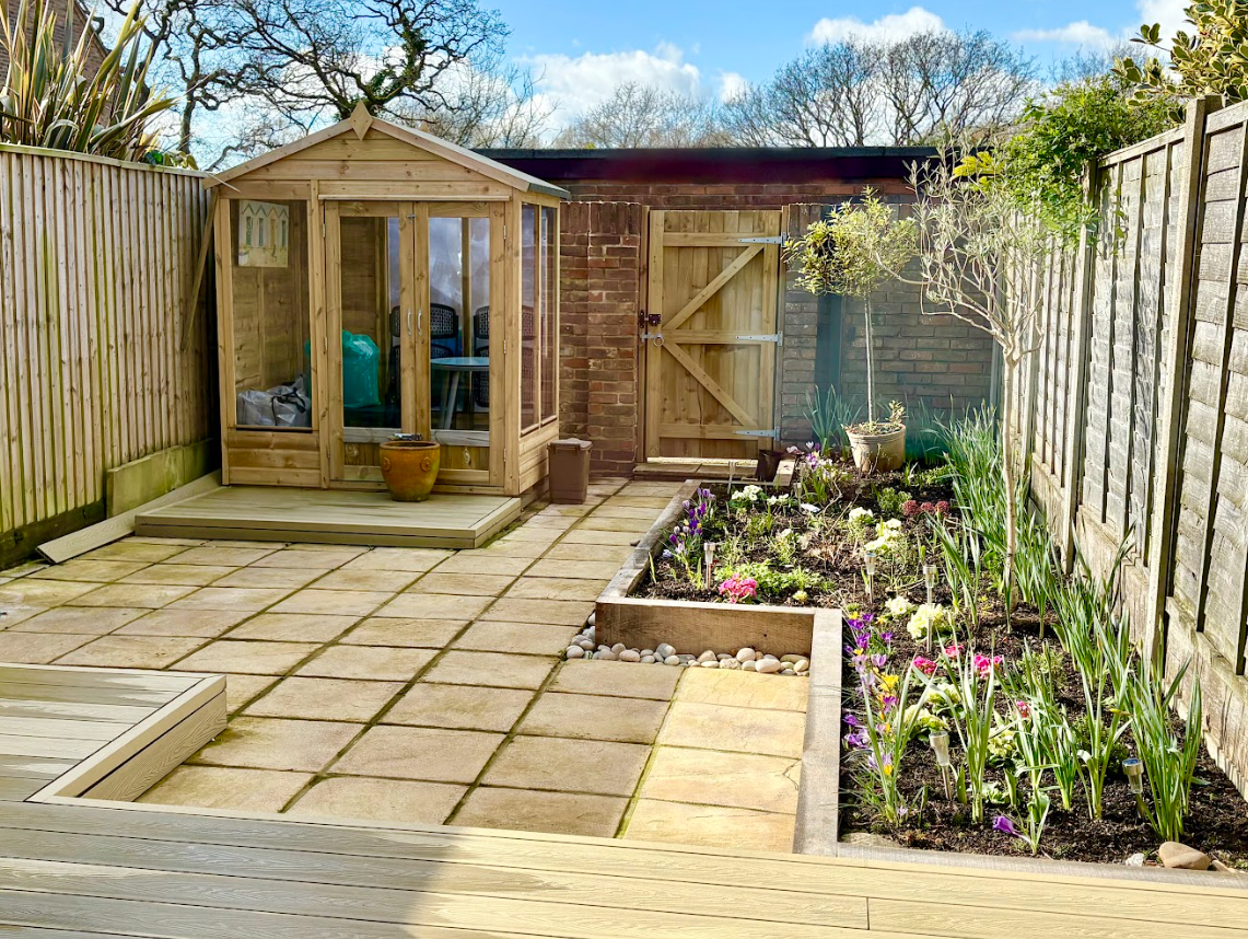 There is a shed in the backyard with a garden in front of it.