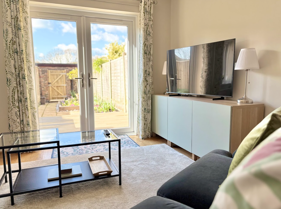 A living room with a couch , television , coffee table and sliding glass doors.