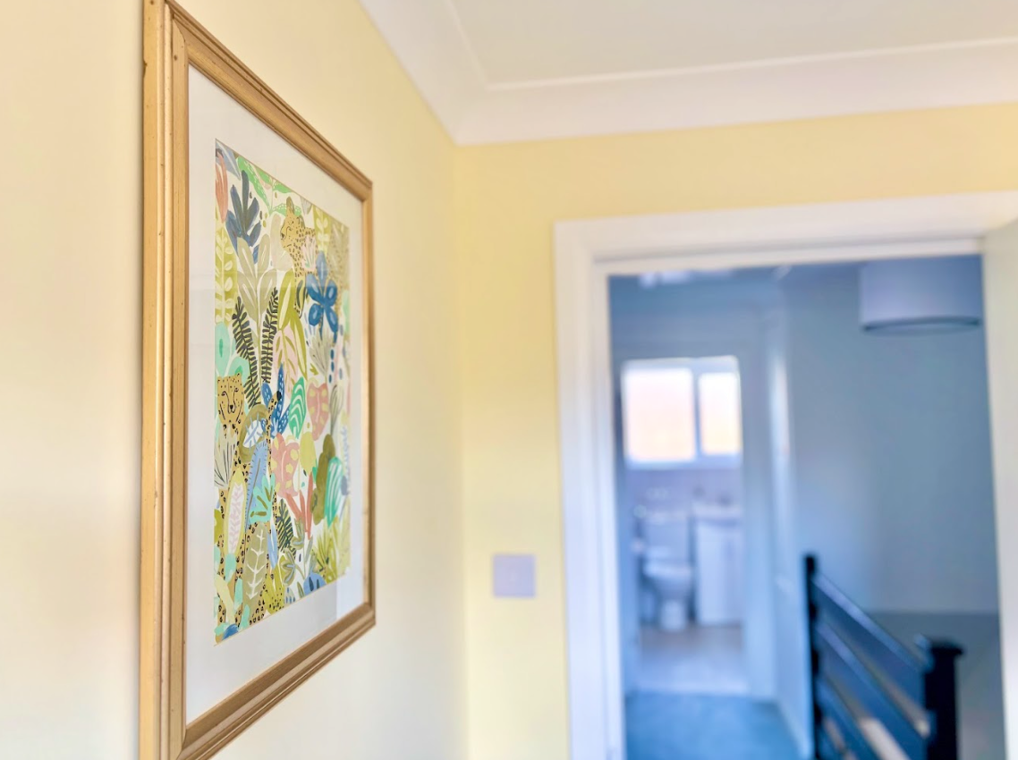 A framed picture hangs on a wall in a hallway