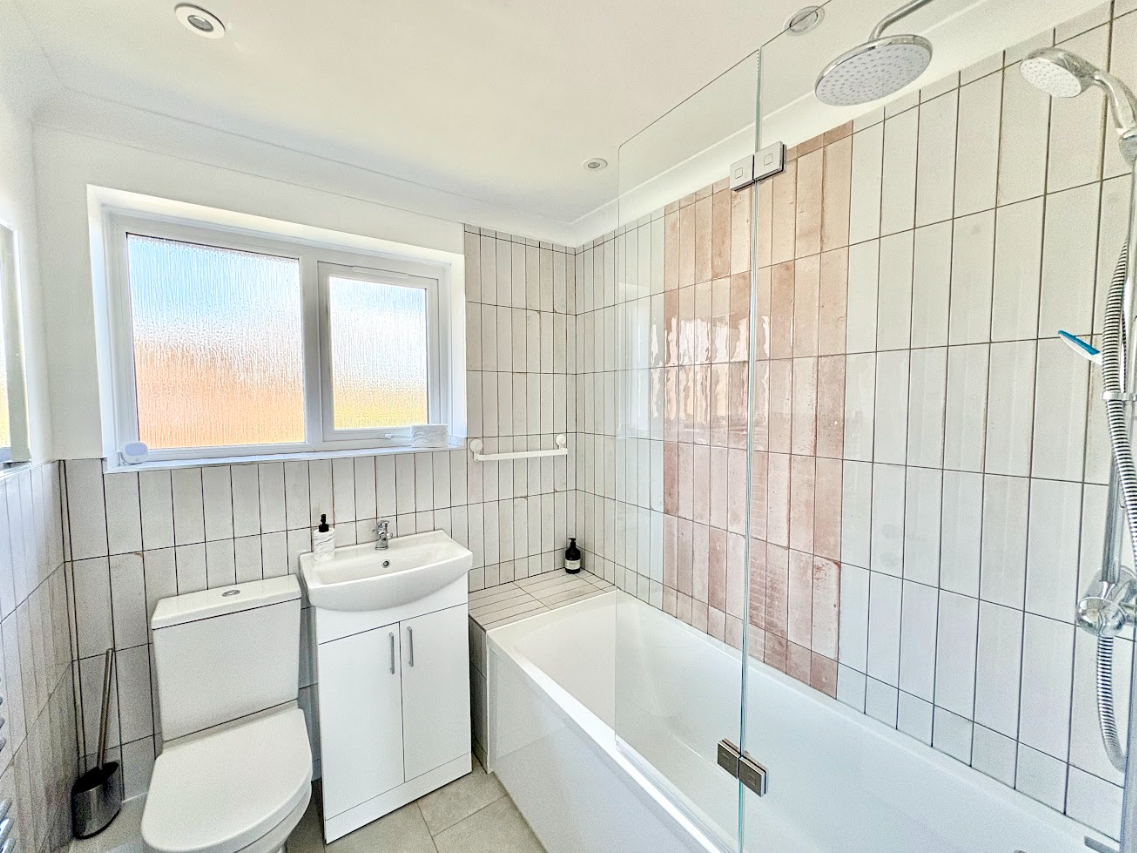 A bathroom with a toilet , sink , bathtub and shower.